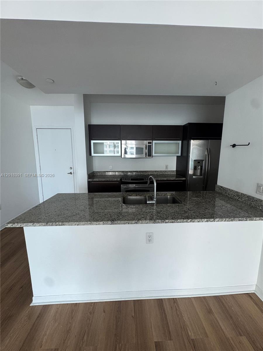 A kitchen features dark wood cabinets, granite countertops, stainless steel appliances, and a breakfast bar — 951 N Brickell Ave # 3001, Miami FL 33131, MIAMI, FL