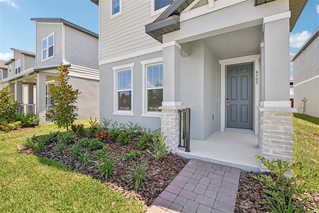 A gray two-story house features a covered front porch, stone pillars, and a landscaped yard — 4505 CROSS PRAIRIE PARKWAY, ST CLOUD, FL