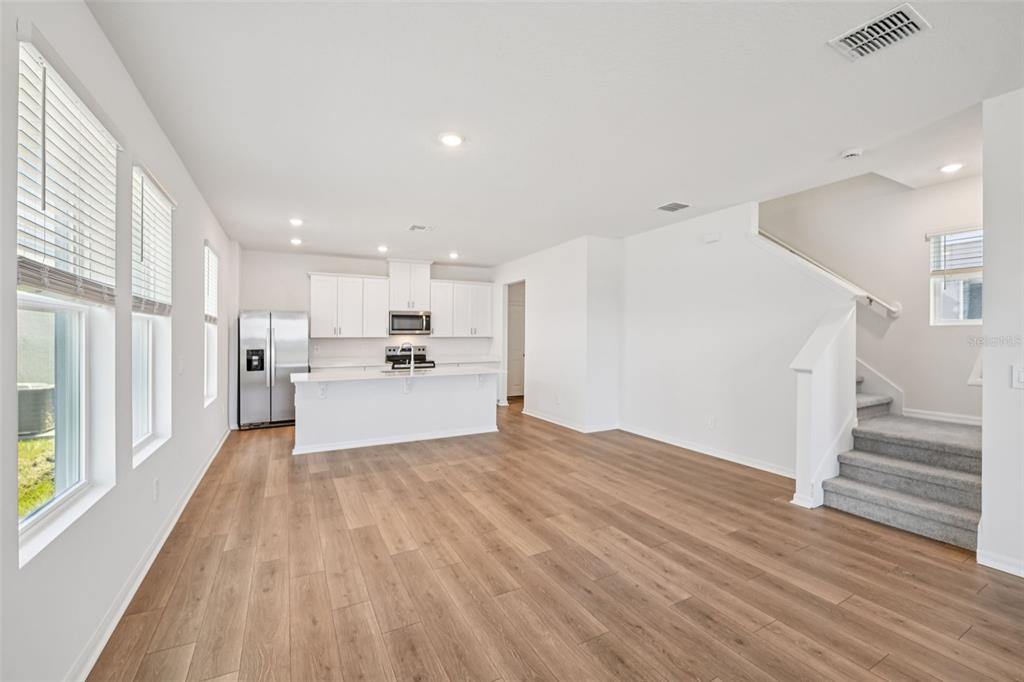 An open-concept kitchen and living area features white cabinetry, a kitchen island, and stairs — 4505 CROSS PRAIRIE PARKWAY, ST CLOUD, FL