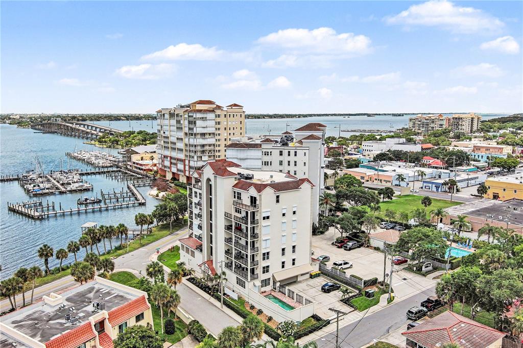 An aerial view shows a multi-story apartment building near a marina and a long bridge — 19 N INDIAN RIVER DRIVE UNIT PH-1, COCOA, FL