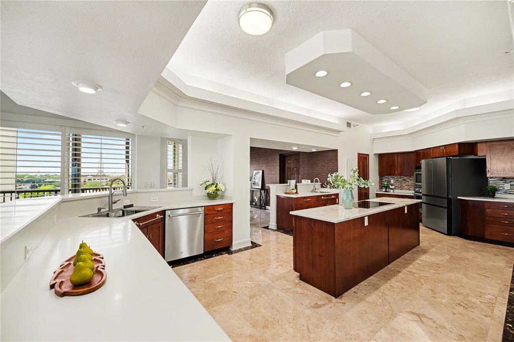 A modern kitchen features dark wood cabinets, white countertops, a central island, and tile flooring — 19 N INDIAN RIVER DRIVE UNIT PH-1, COCOA, FL