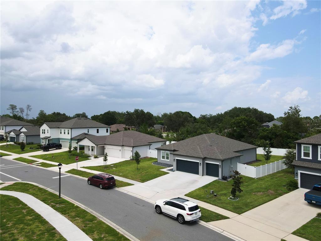 An aerial view of a suburban street featuring several modern single-family homes and parked cars — 1663 MEADOWLARK DRIVE, DELTONA, FL