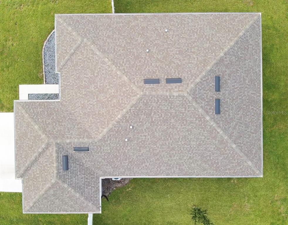 An aerial view shows the shingled roof of a house surrounded by a green lawn — 1663 MEADOWLARK DRIVE, DELTONA, FL