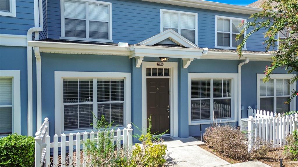 A blue two-story townhouse exterior features a brown front door and a white picket fence — 2208 SAN VITTORINO CIRCLE UNIT 104, KISSIMMEE, FL