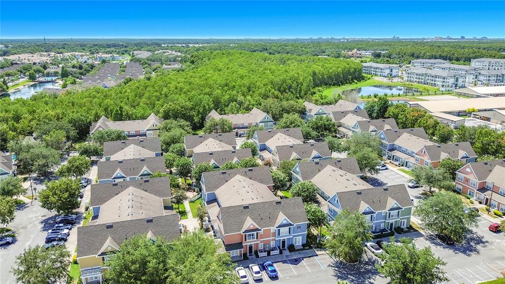 An aerial view shows multiple multi-story residential townhome buildings surrounded by trees and parking lots — 2208 SAN VITTORINO CIRCLE UNIT 104, KISSIMMEE, FL