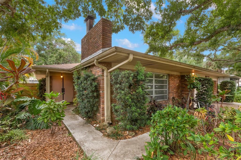 A brick house with a chimney and a concrete walkway surrounded by lush landscaping — 2616 S TORONTO AVENUE, TAMPA, FL