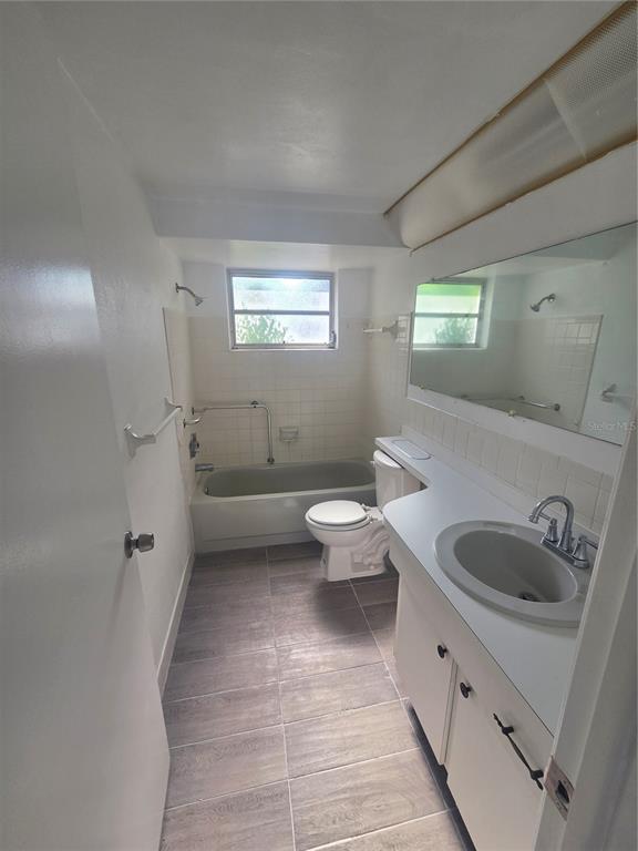 A bathroom features a vanity, toilet, and a bathtub with a shower head and grab bar — 12213 PARTRIDGE HILL ROW, HUDSON, FL