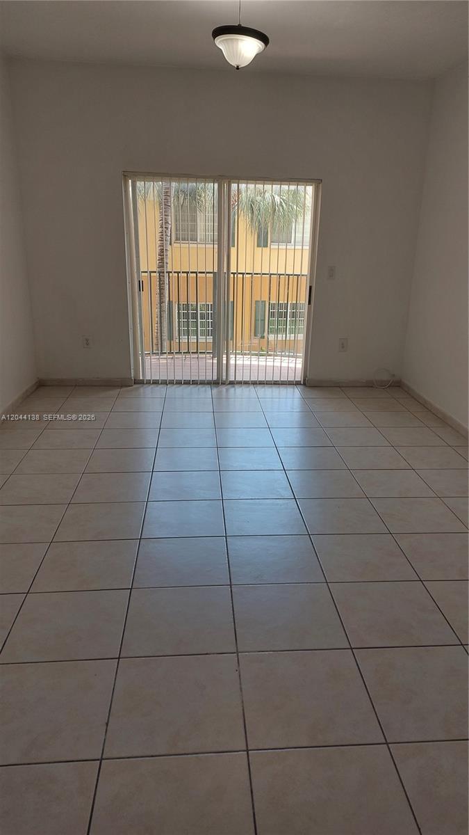 A room with light-colored tile flooring, a ceiling light fixture, and sliding glass balcony doors — 7290 NW 114th Ave # 7, Doral FL 33178, DORAL, FL