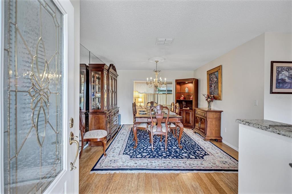 A dining room with a wooden table, chairs, hutch, and a blue patterned area rug — 1743 MACDONNELL DRIVE, PALM HARBOR, FL