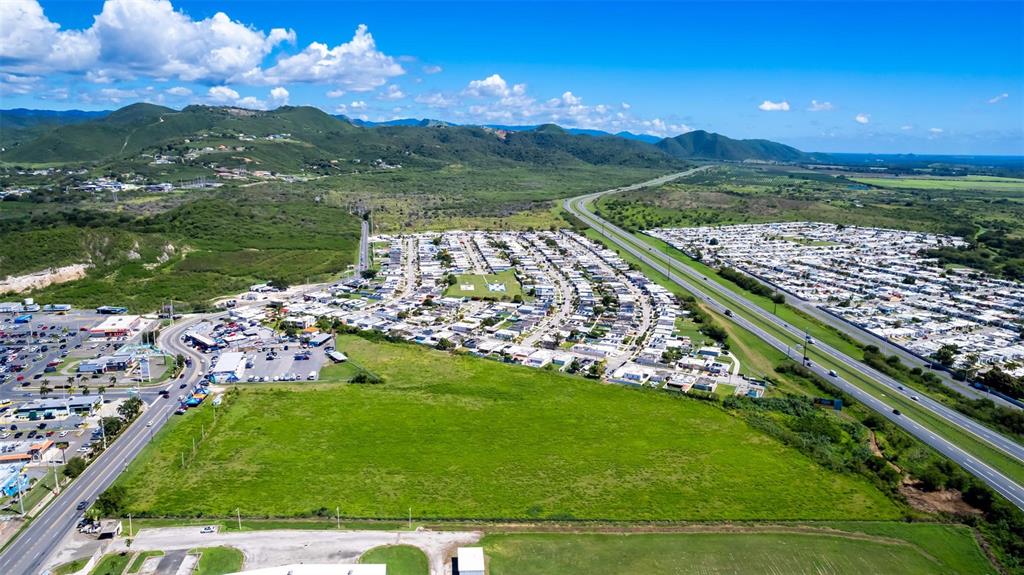An aerial view shows a large green field adjacent to a residential neighborhood and highway — PR-153 STREET, SANTA ISABEL, PR