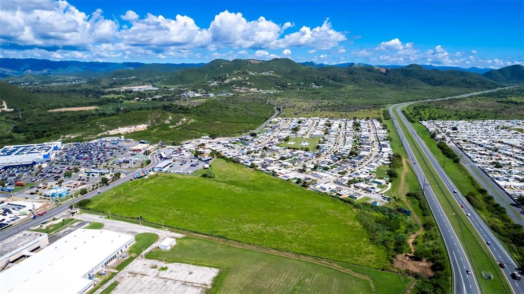 An aerial view shows a large green field bordered by a highway and residential neighborhood — PR-153 STREET, SANTA ISABEL, PR