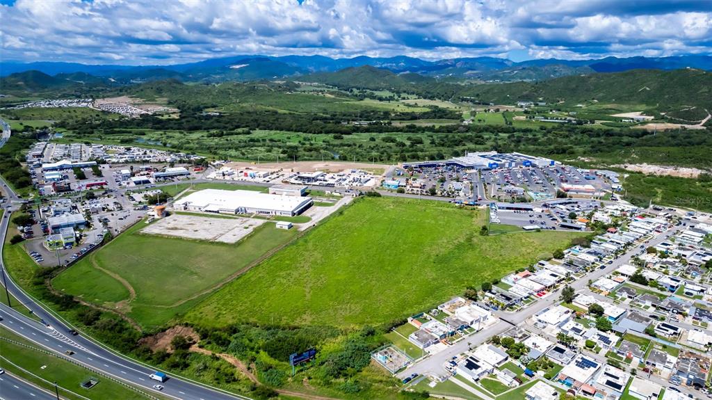An aerial view shows a large green field adjacent to commercial buildings and residential neighborhoods — PR-153 STREET, SANTA ISABEL, PR