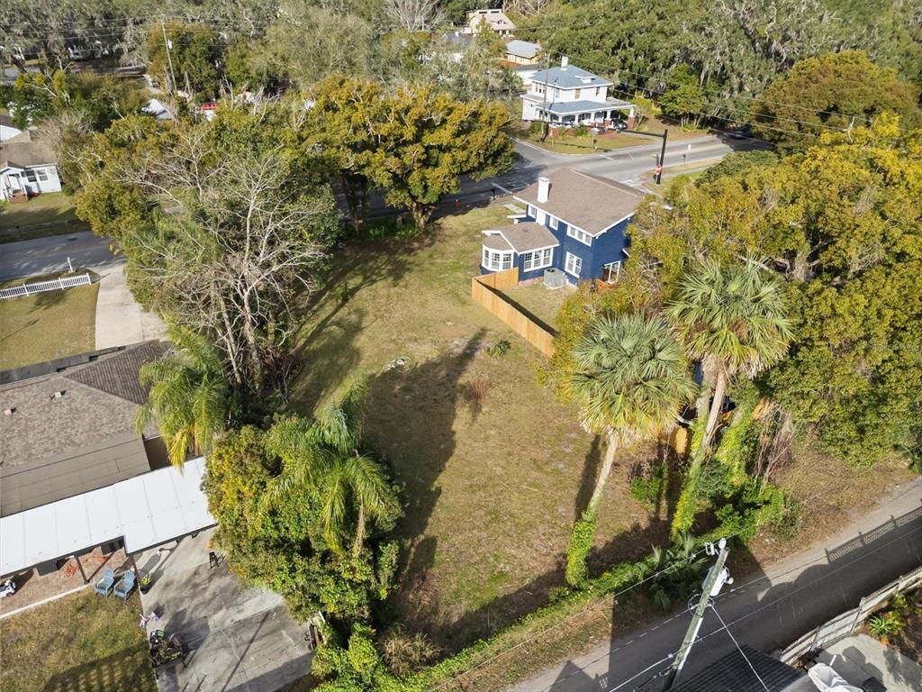 An aerial view shows a vacant residential lot next to a blue house and trees — TBD SANFORD AVENUE, SANFORD, FL