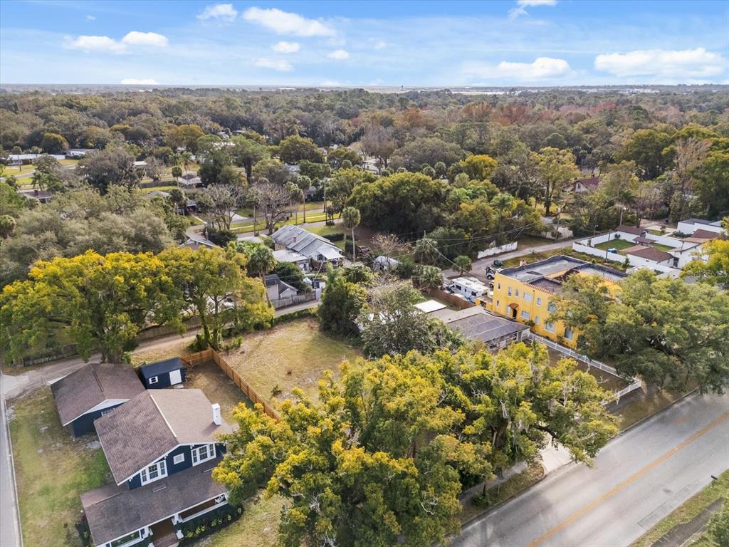 An aerial view shows a vacant lot situated between a dark house and a yellow building — TBD SANFORD AVENUE, SANFORD, FL