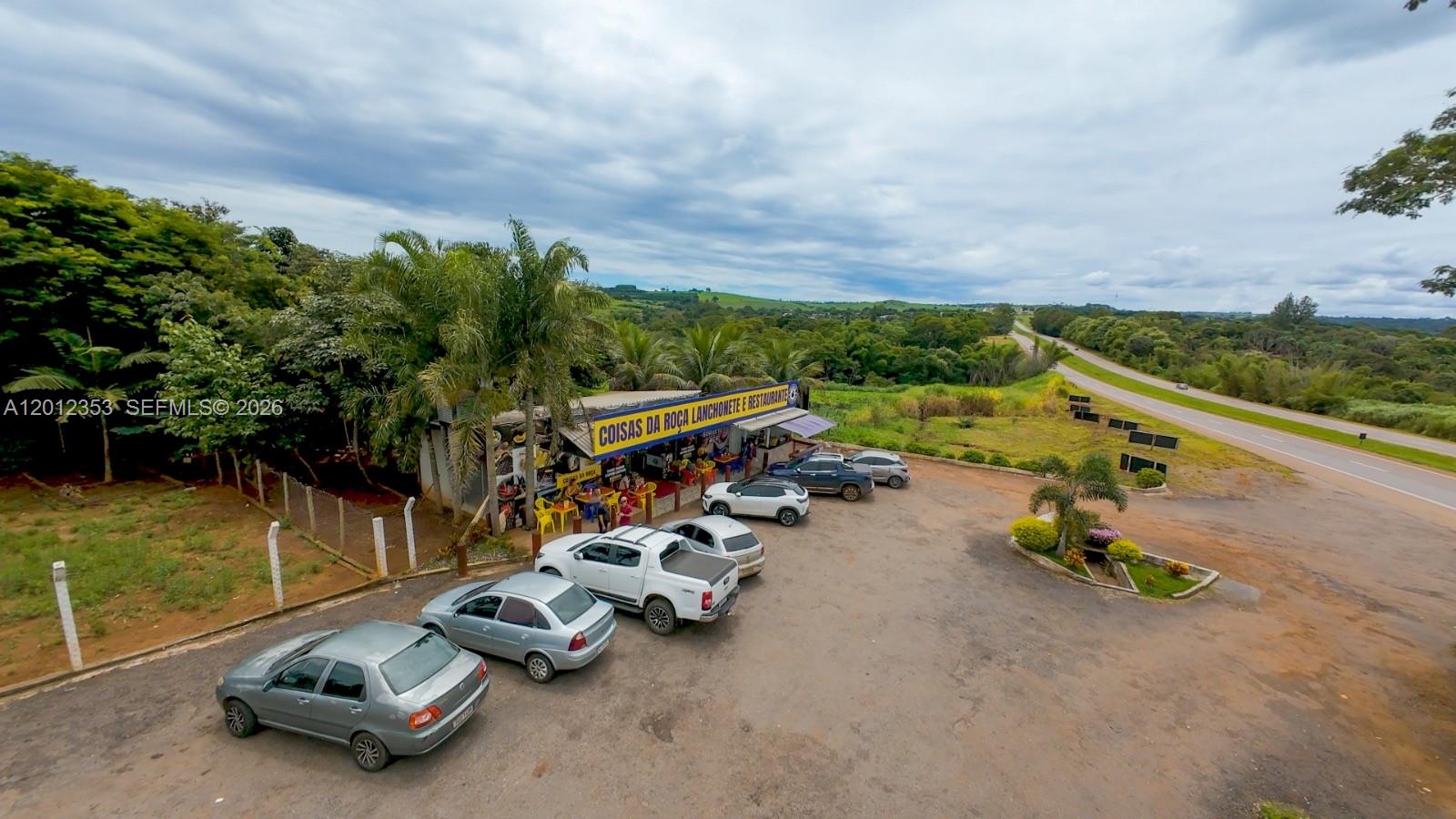 An aerial view shows a roadside restaurant with a parking lot and surrounding rural landscape — BR153 km114, GO, GO