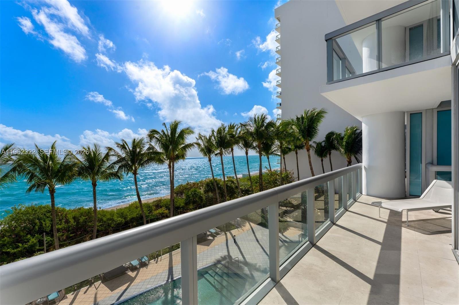 A balcony with a glass railing overlooks a swimming pool, palm trees, and the ocean — 6899 Collins Ave # 403, Miami Beach FL 33141, MIAMI BEACH, FL