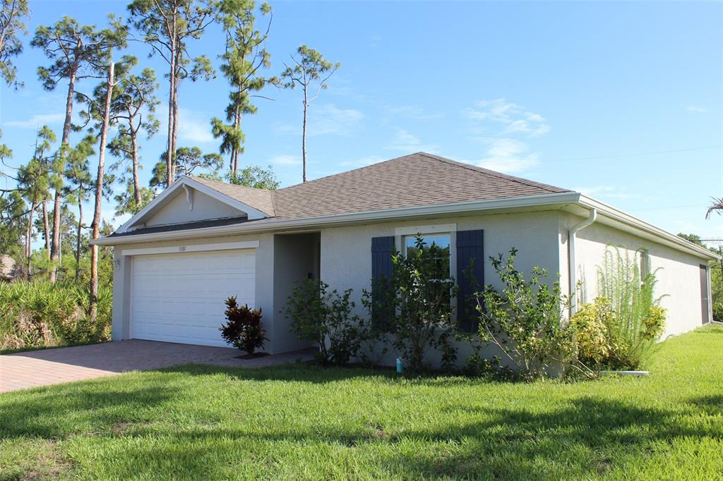 A single-story house with a white garage, blue shutters, and a lawn under a blue sky — 5501 KEMPSON LANE, PORT CHARLOTTE, FL