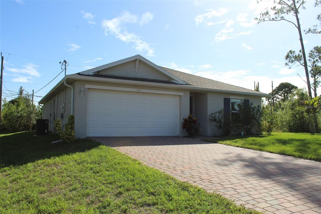 A single-story house with a white garage door and a paved driveway under a blue sky — 5501 KEMPSON LANE, PORT CHARLOTTE, FL