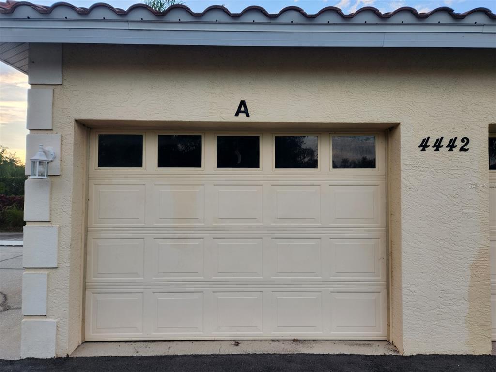 A beige garage door with windows and the letter A above it on a building — 4442 CORSO VENETIA BOULEVARD UNIT A14, VENICE, FL