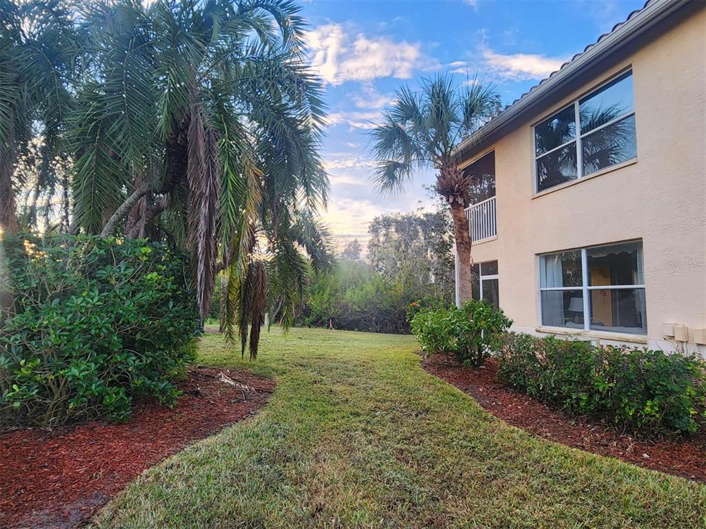 A two-story tan building sits next to a grassy lawn with palm trees — 4442 CORSO VENETIA BOULEVARD UNIT A14, VENICE, FL