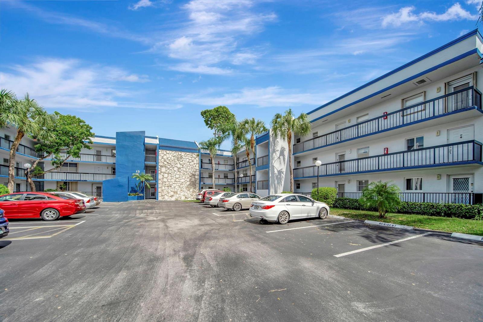 A multi-story apartment building with a blue and white exterior features a parking lot — 3100 Holiday Springs Boulevard # 305, Margate FL 33063, MARGATE, FL
