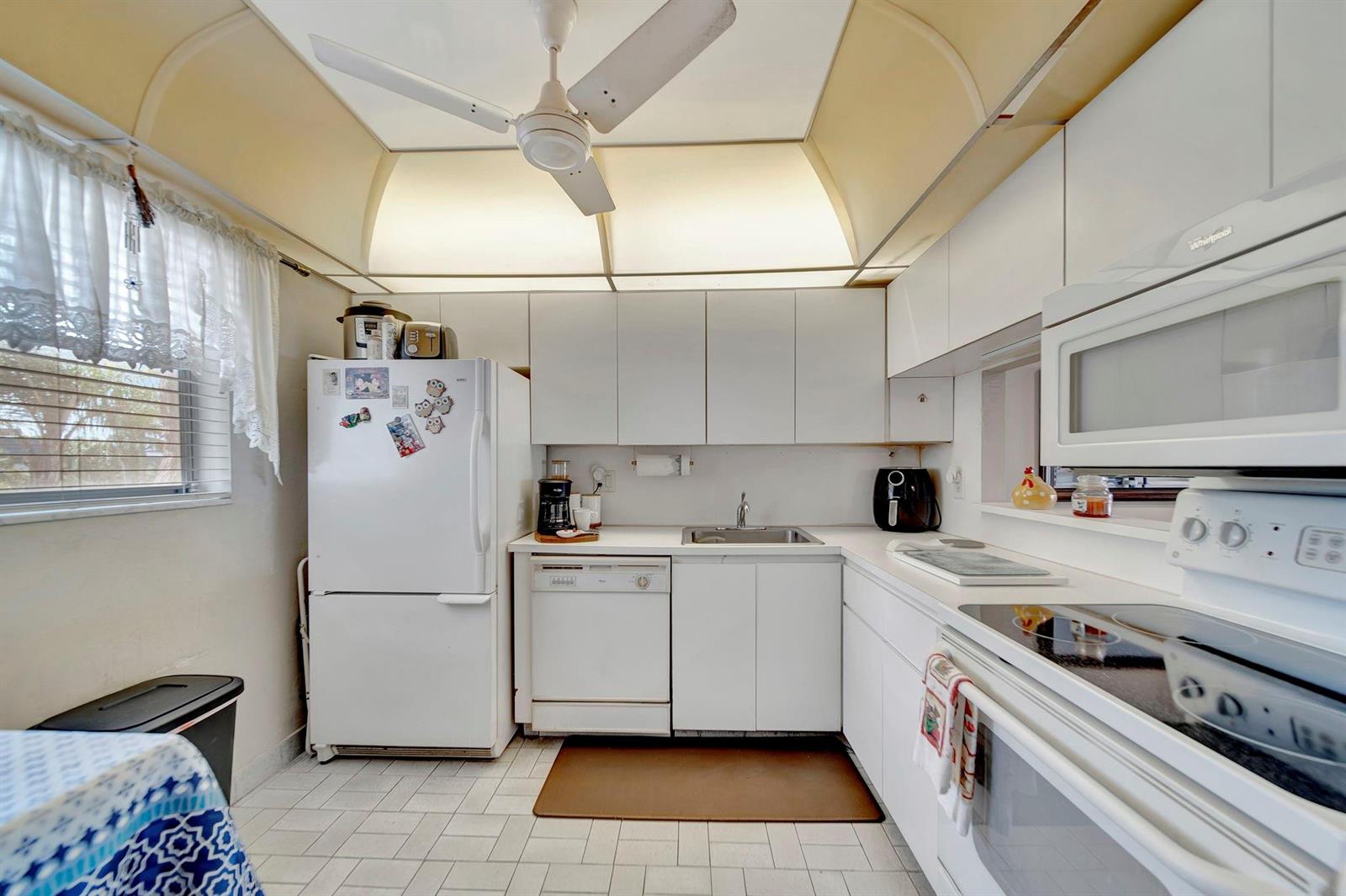 A kitchen with white cabinets, white appliances, a ceiling fan, and tiled flooring — 3100 Holiday Springs Boulevard # 305, Margate FL 33063, MARGATE, FL