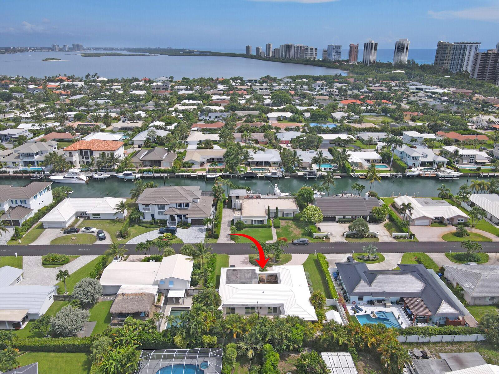 An aerial view shows a residential neighborhood with a canal and a marked house — 1211 Bimini Lane, Singer Island FL 33404, SINGER ISLAND, FL