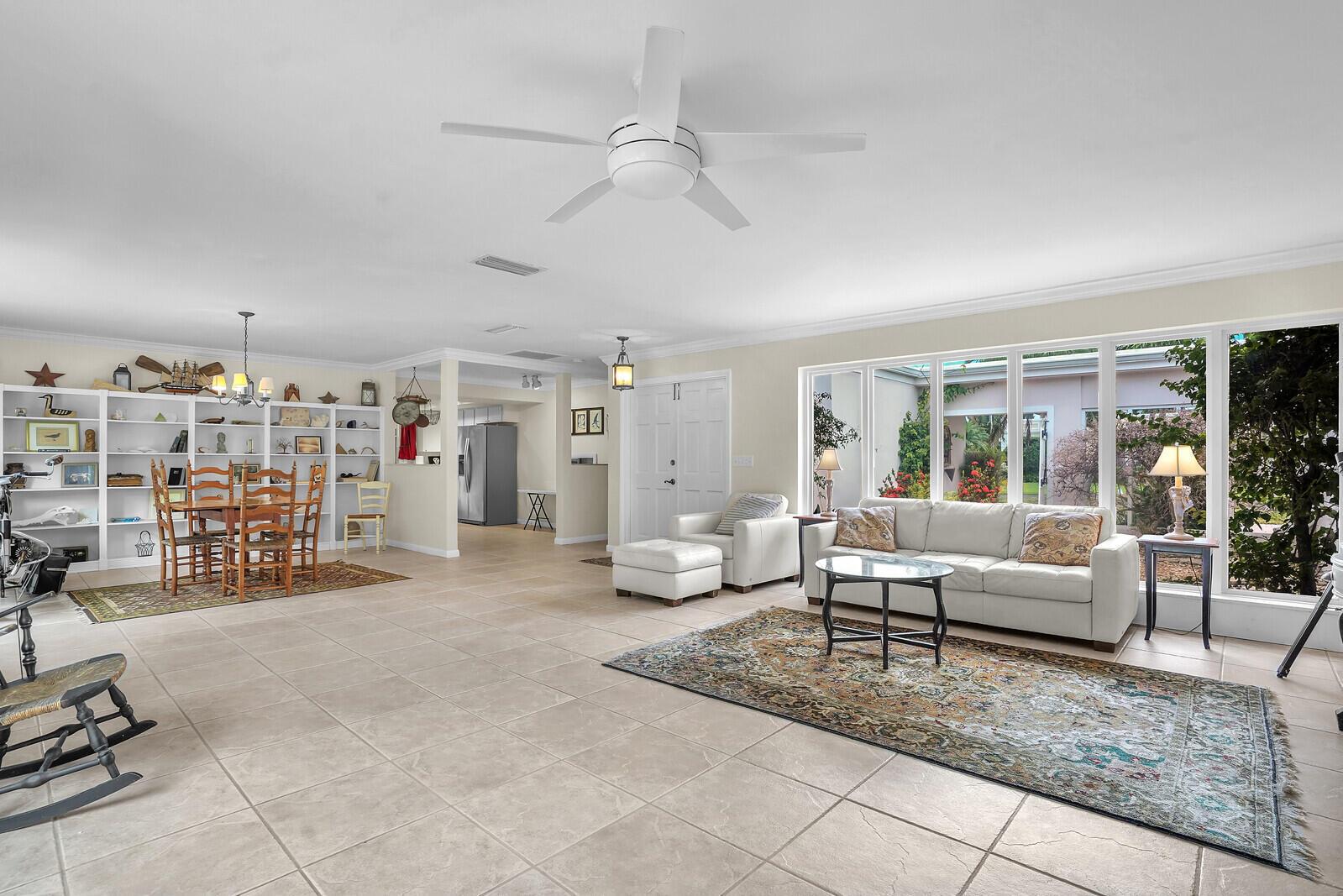 A spacious open-concept living and dining area with tile floors, large windows, and white shelving — 1211 Bimini Lane, Singer Island FL 33404, SINGER ISLAND, FL
