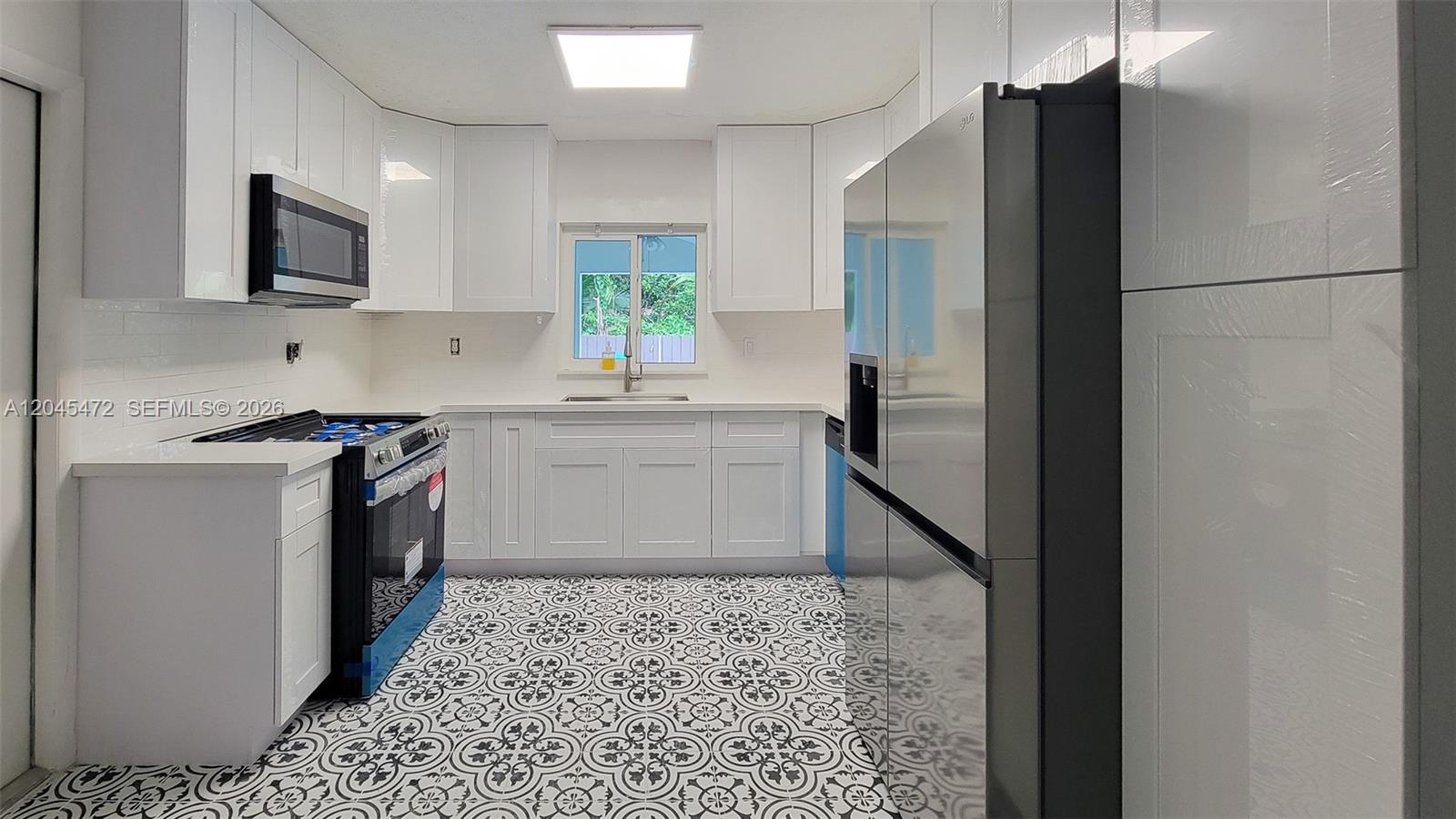 A bedroom features a gray upholstered bed, a woven pendant light, and white louvered closets — 14325 NE 8th Ave, North Miami FL 33161, NORTH MIAMI, FL
