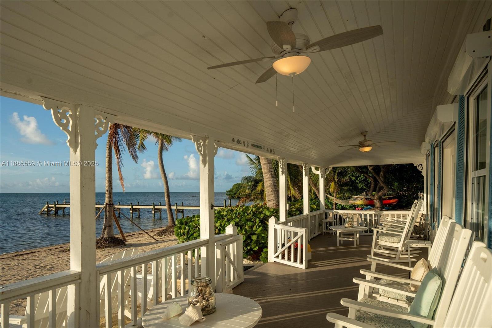A covered wooden porch features white railings, rocking chairs, and a view of the ocean — 109 Columbus Dr, Islamorada FL 33036, ISLAMORADA, FL