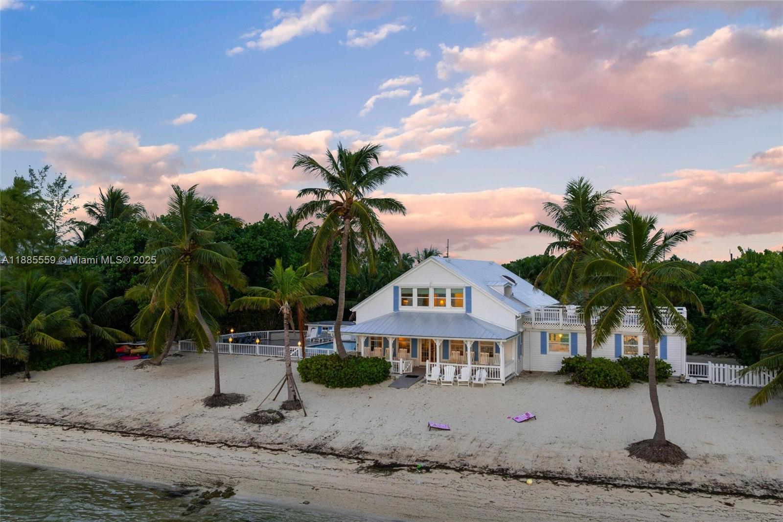 A white house with a metal roof sits on a sandy beach with palm trees — 109 Columbus Dr, Islamorada FL 33036, ISLAMORADA, FL