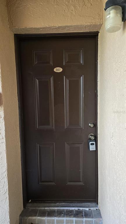 A brown six-panel entry door with a lockbox and unit number 307 — 5214 VIA HACIENDA CIRCLE UNIT A307, ORLANDO, FL