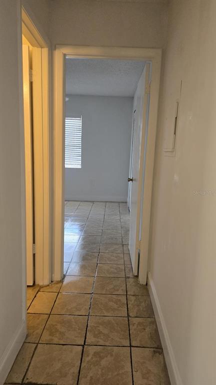 A hallway with light-colored tile flooring leads toward a bedroom with a window — 5214 VIA HACIENDA CIRCLE UNIT A307, ORLANDO, FL