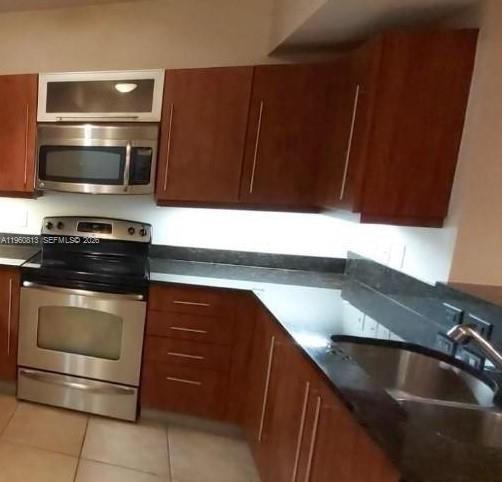 A kitchen features cherry wood cabinets, stainless steel appliances, and dark granite countertops — 7350 SW 89th St # 1804S, Miami FL 33156, MIAMI, FL