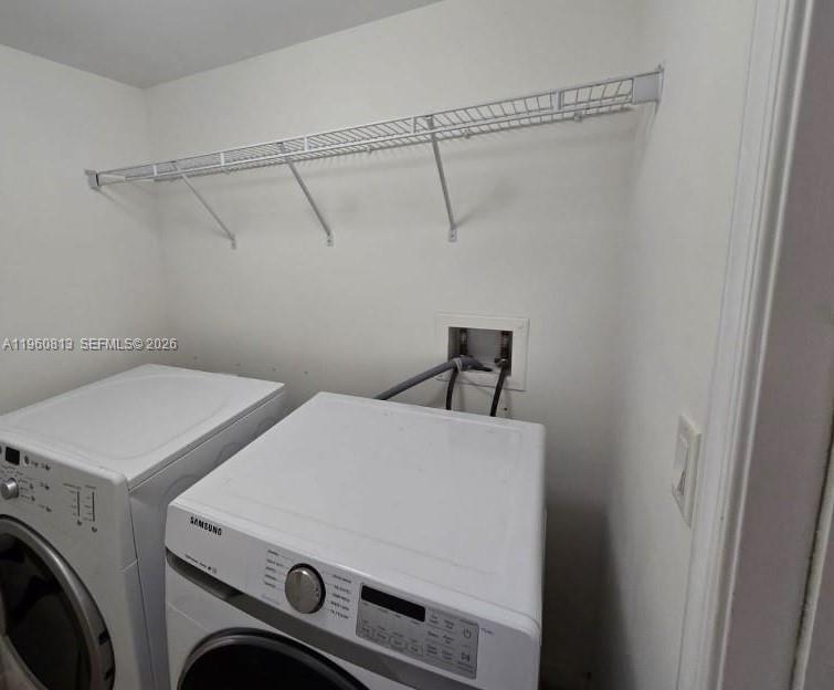 A laundry room features a white washer and dryer beneath a wire wall shelf — 7350 SW 89th St # 1804S, Miami FL 33156, MIAMI, FL