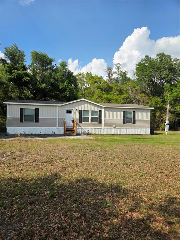 A single-story manufactured home with beige siding and black shutters sits on a grassy lot — 5211 TURTLE DOVE TRAIL, LAKELAND, FL