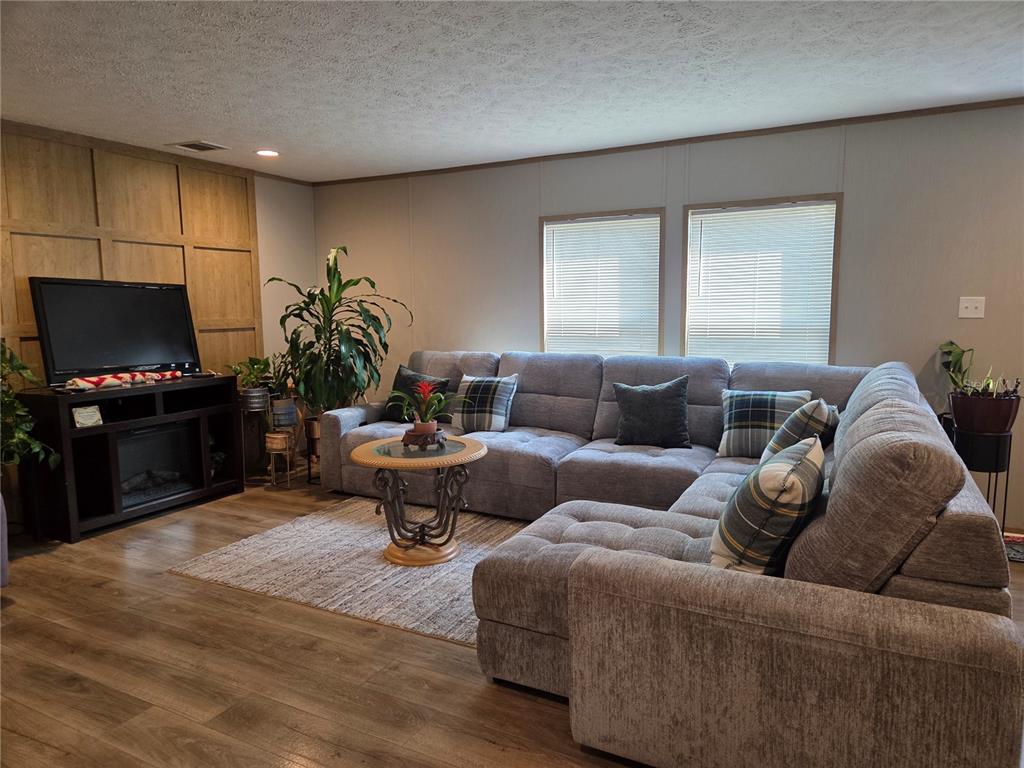 A living room features a large gray sectional sofa, wood-paneled accent wall, and wood flooring — 5211 TURTLE DOVE TRAIL, LAKELAND, FL