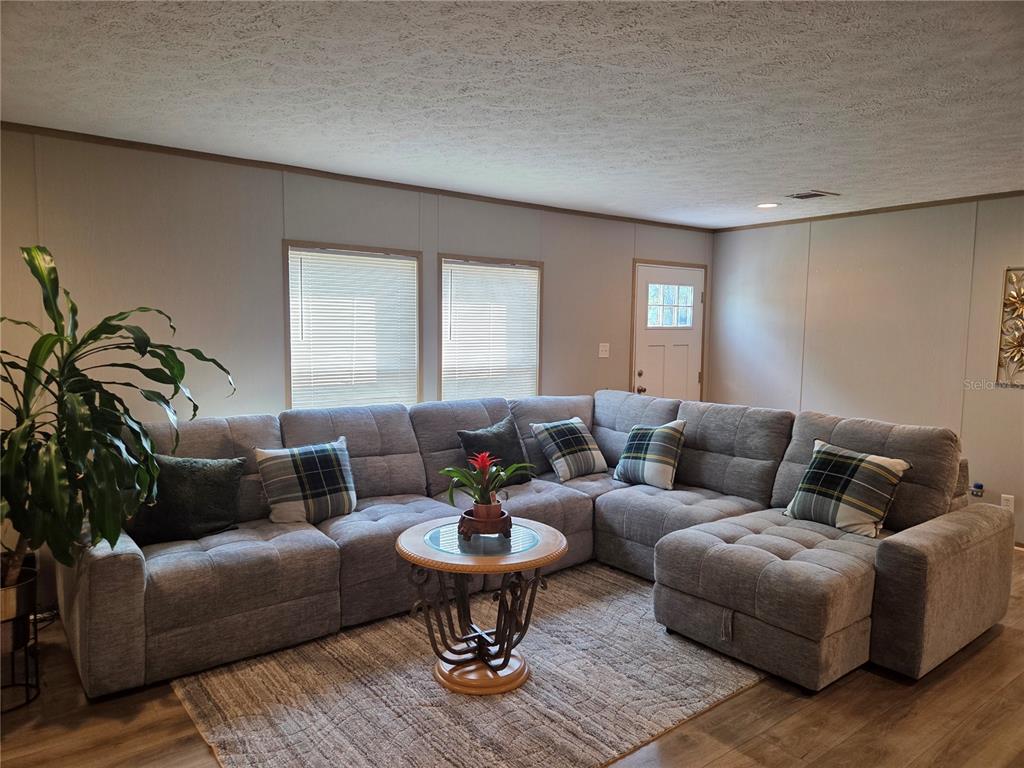 A living room features a large gray sectional sofa, a round coffee table, and windows — 5211 TURTLE DOVE TRAIL, LAKELAND, FL