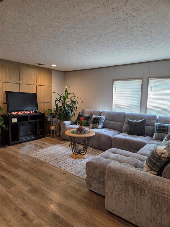 A living room features a grey sectional sofa, wood-paneled accent wall, and wood-look flooring — 5211 TURTLE DOVE TRAIL, LAKELAND, FL