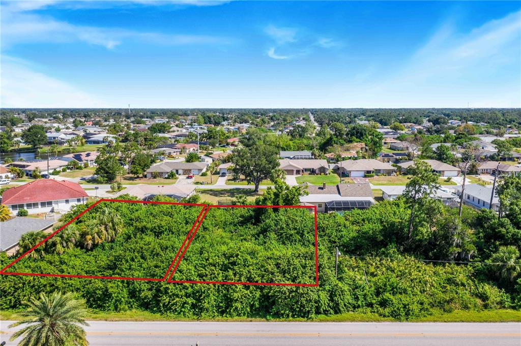 An aerial view shows two adjacent, undeveloped, tree-covered lots outlined in red along a road — 23108 & 23116 OLEAN BOULEVARD, PORT CHARLOTTE, FL