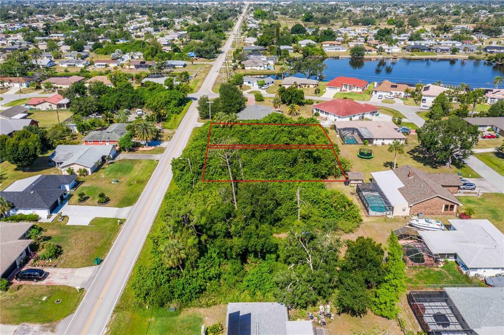 An aerial view shows a vacant, tree-covered lot outlined in red within a residential neighborhood — 23108 & 23116 OLEAN BOULEVARD, PORT CHARLOTTE, FL