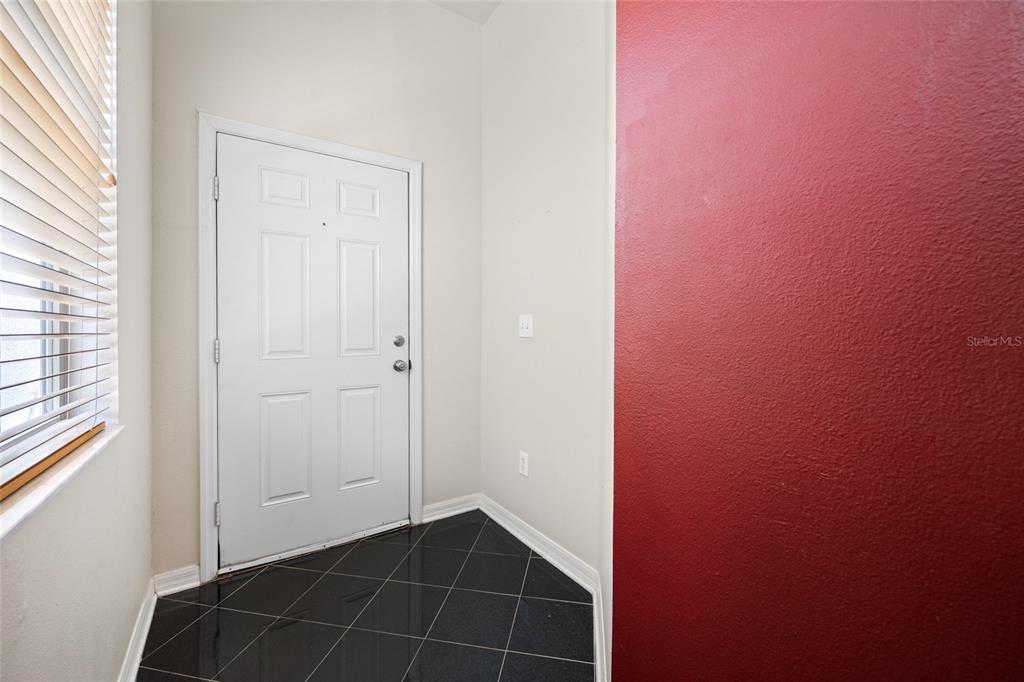 An entryway features a white door, black tile flooring, and a bold red accent wall — 10409 CRIMSON PARK LANE UNIT 110, TAMPA, FL