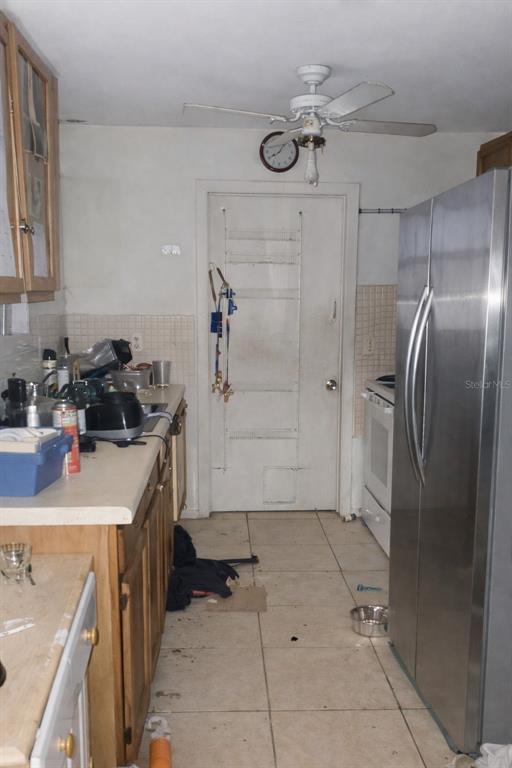A kitchen features wood cabinets, a stainless steel refrigerator, a ceiling fan, and tiled flooring — 7393 GRAND AVENUE, WINTER PARK, FL