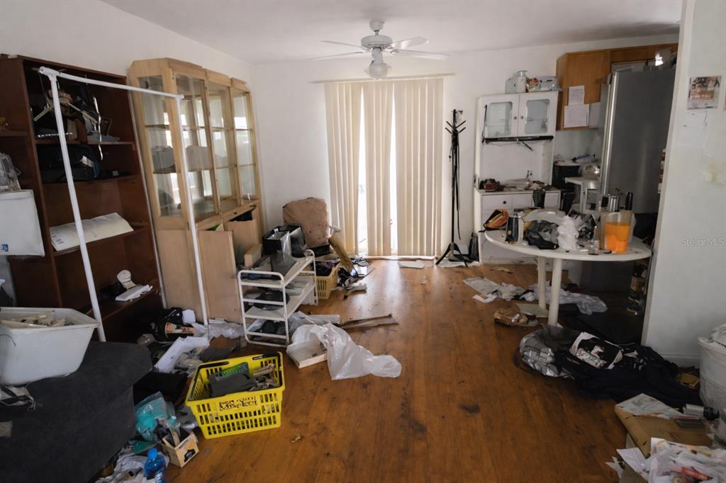 A cluttered room with wood-look flooring, a ceiling fan, and a sliding glass door — 7393 GRAND AVENUE, WINTER PARK, FL