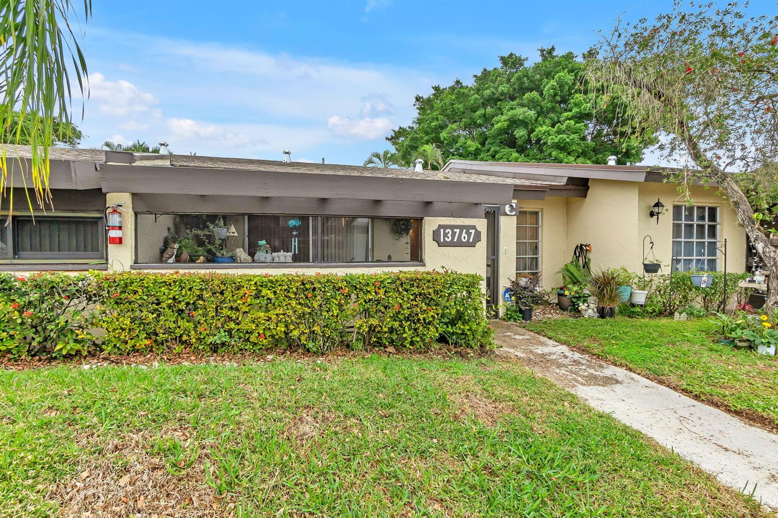 A single-story house with a flat roof, large front window, and a landscaped front yard — 13767 Via Aurora # C, Delray Beach FL 33484, DELRAY BEACH, FL