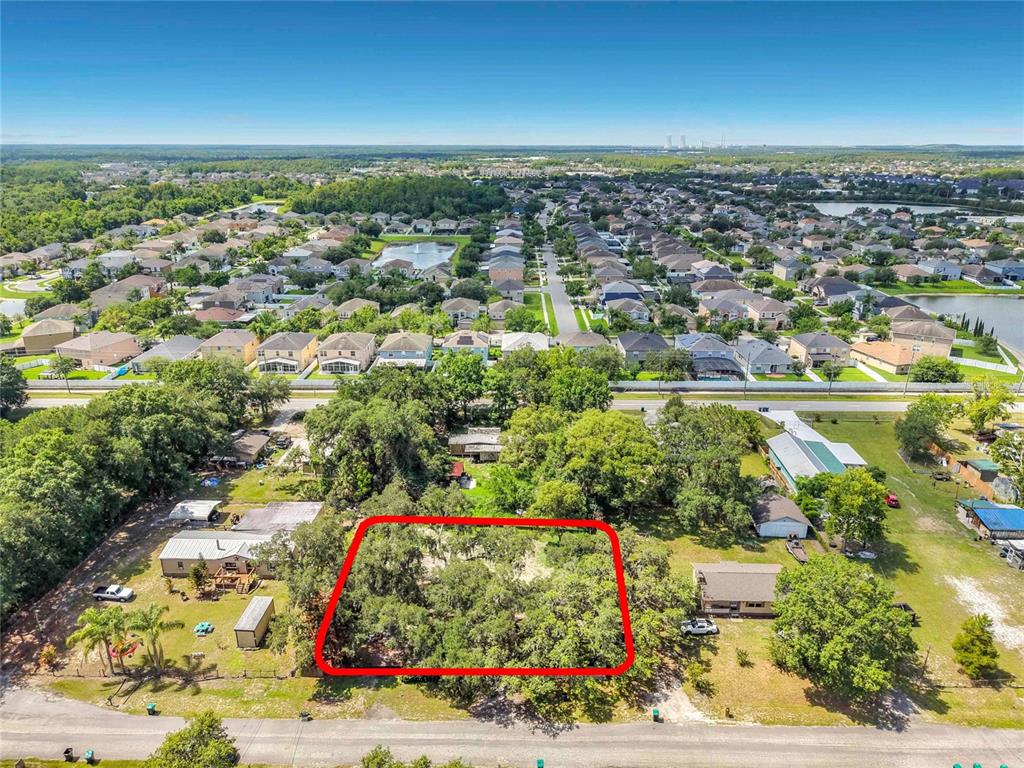 An aerial view shows a rectangular, tree-covered vacant lot outlined in red along a road — 15832 BERMUDA STREET, ORLANDO, FL