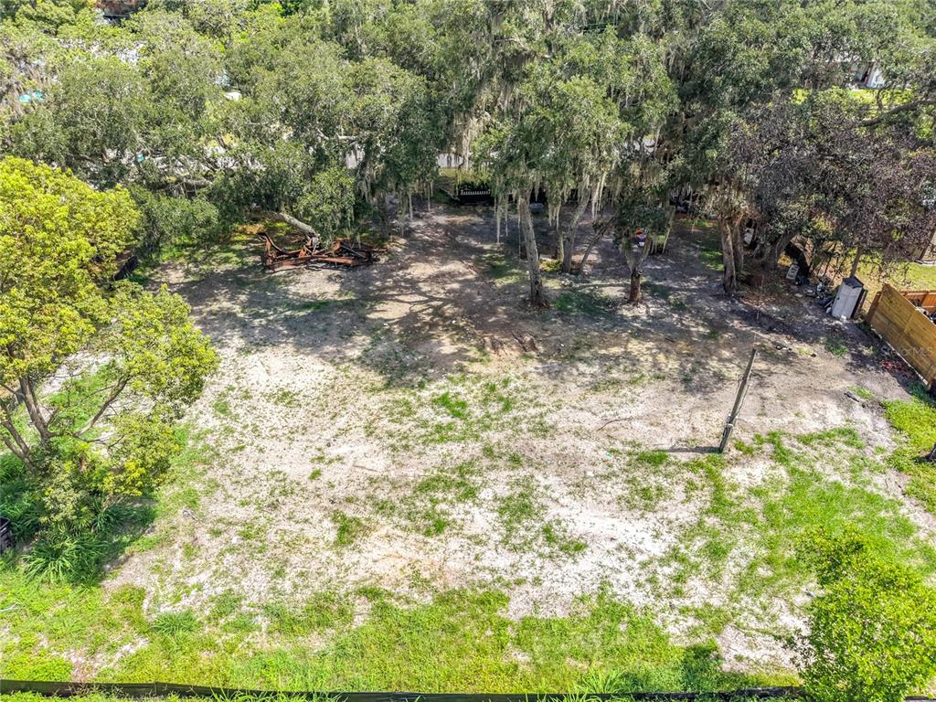 An elevated view of a vacant, partially shaded lot with scattered trees and sandy ground — 15832 BERMUDA STREET, ORLANDO, FL