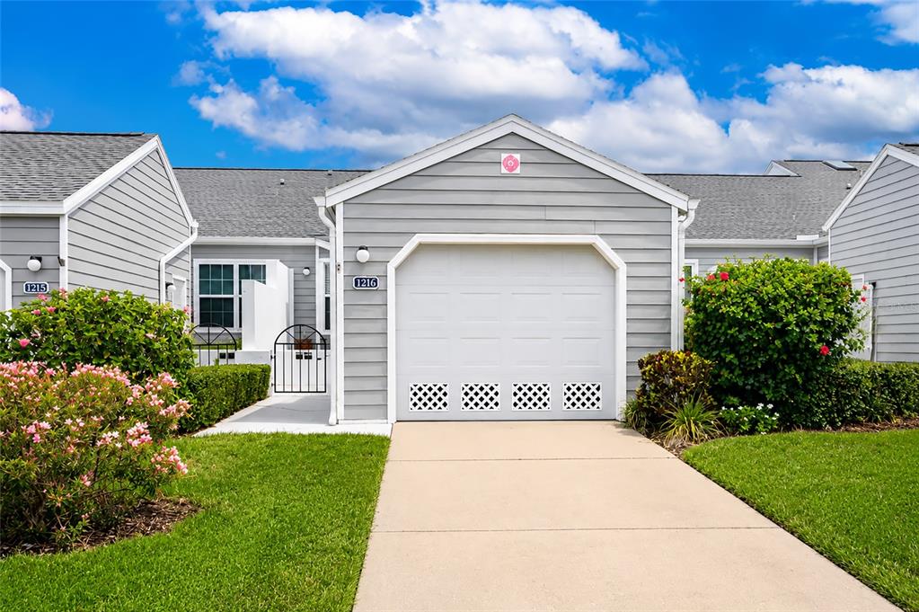 A gray-sided residential building features a white garage door, a concrete driveway, and landscaping — 1216 SPOONBILL LANDINGS CIRCLE, BRADENTON, FL