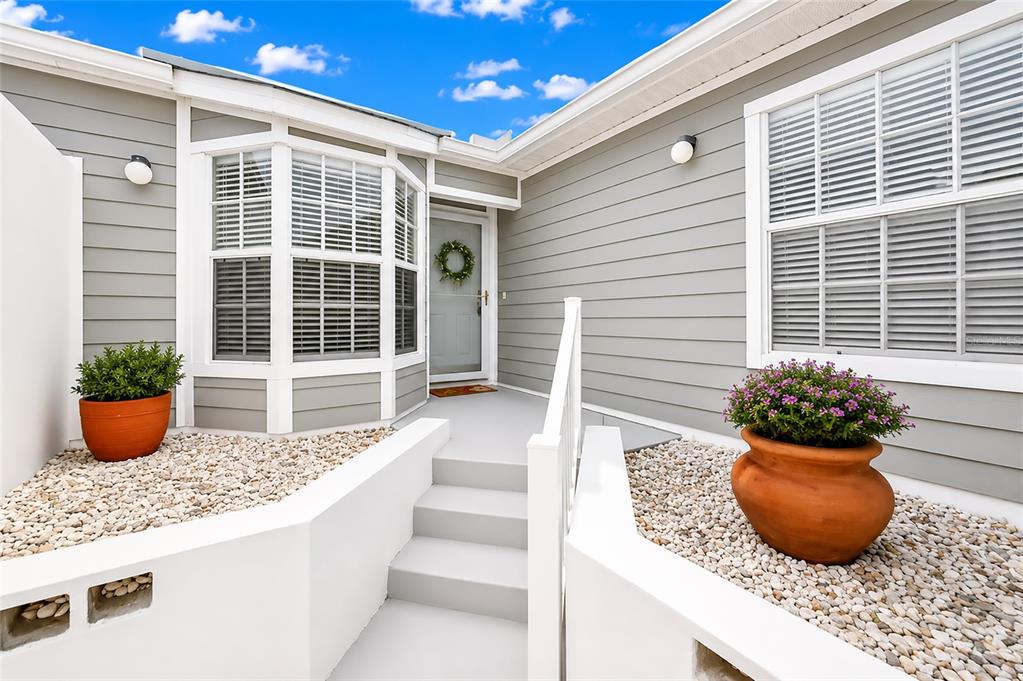 The exterior of a house features gray siding, a front door, and two potted plants — 1216 SPOONBILL LANDINGS CIRCLE, BRADENTON, FL