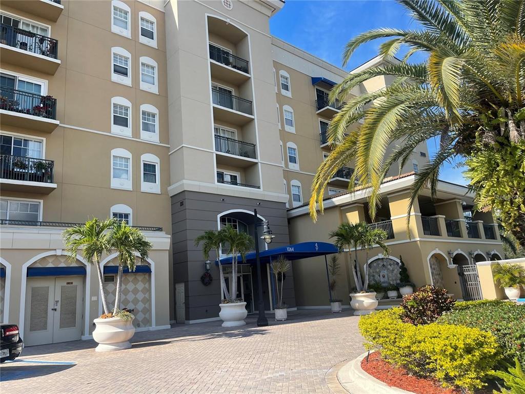 The exterior of a multi-story apartment building features a blue awning over the main entrance — 1064 N TAMIAMI TRAIL UNIT 1122, SARASOTA, FL